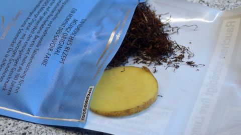 Ein Stück rohe Kartoffel liegt neben trockenem Tabak in einer offenen Verpackung auf einer Oberfläche.