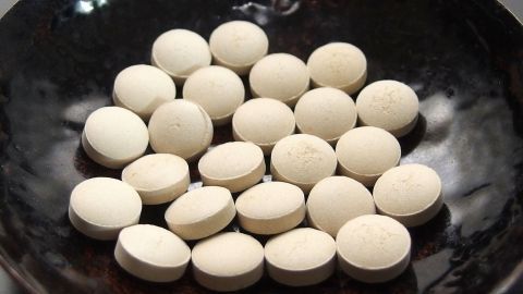 Weiße Tabletten liegen in einer dunklen Schale, die als Bierhefe zur Unterstützung bei Pickeln dienen.