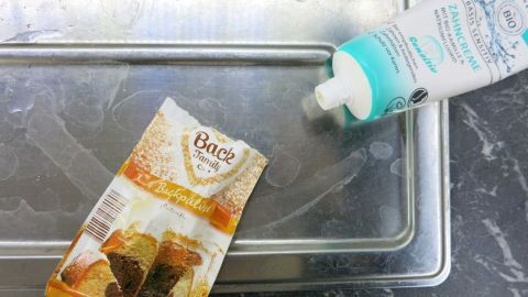 Die Spüle in der Küche kann man mit Backpulver blitzeblank putzen. Es funktioniert auch sehr gut mit billiger Zahnpasta. Auf einer Arbeitsfläche liegt eine Packung Spülmittel neben einer Flasche Reinigungsmittel, bereit zum Spülen.