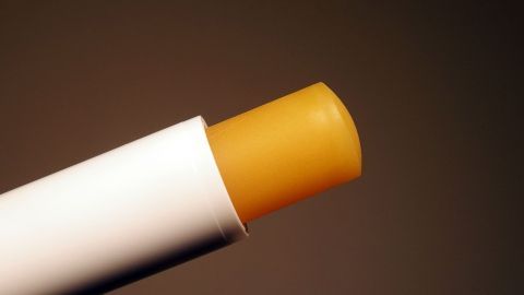 Ein Lippenstift, der kaputt ist, wird in naher Ansicht gezeigt, mit einem gelben Stiftteil, auf einem dunklen Hintergrund.