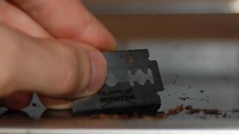 Reinige Dein Glaskeramikfeld effektiv mit einer Rasierklinge. Die sanfte Methode entfernt eingebrannte Rückstände mühelos und ohne Kratzer. Achte darauf, die Klinge flach zu halten, um Beschädigungen zu vermeiden. Eine Hand hält eine Rasierklinge und säubert ein Glaskeramikfeld, indem sie Schmutz von der Oberfläche kratzt.