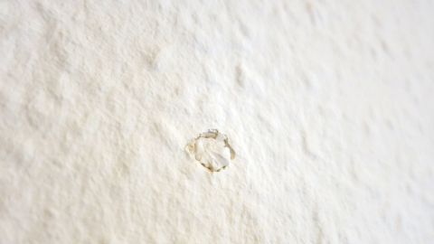 Ein Nagel steckt in einer weißen Wand, um Papiertaschentücher zu befestigen, in einem minimalistischen Raum ohne weitere Dekoration.