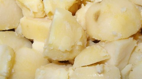 Gekochte und gestückelte Salzkartoffeln liegen dicht beieinander, bereit zum Servieren als Beilage in einer rustikalen Küche.