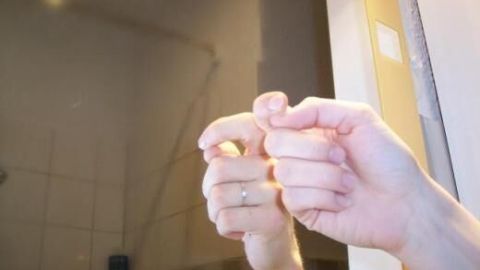 Benutze beschlagene Spiegel und Fensterscheiben, um Warzen zu behandeln. Der Dampf und das Kondenswasser sollen helfen. Reibe die betroffene Stelle sanft in den Beschlag des Spiegels, wie auf dem Bild gezeigt. Hände formen ein Symbol vor einem beschlagenen Spiegel im Badezimmer. Keine Texte im Bild.