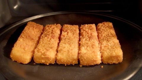 Fischstäbchen sind auf einem Teller in der Mikrowelle erhitzt und warten darauf, serviert zu werden.