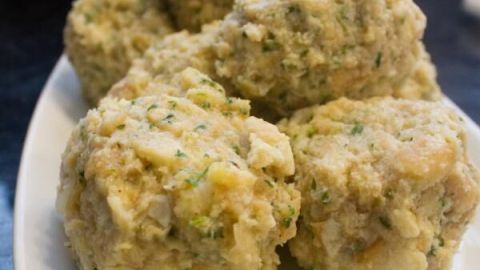 Semmelknödel liegen auf einem weißen Teller, servierbereit, in einer heimischen Kücheneinrichtung.