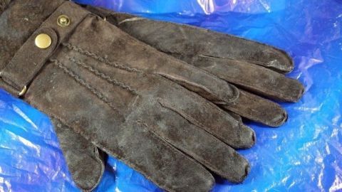 Dunkle Wildlederhandschuhe liegen auf einer blauen Folie und warten darauf, mit Feinwaschmittellösung gereinigt zu werden.
