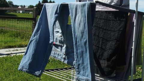 Wäsche bei einer ordentlichen Brise Wind aufhängen und das Bügeln entfällt. Luftige, frisch gewaschene Jeans hängen auf einem Wäscheständer, während ein leichter Wind sanft durch die Landschaft weht.