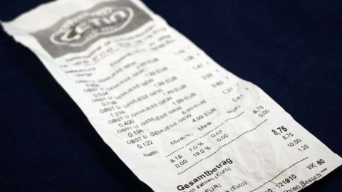 Ein Kassenbon liegt auf einem dunklen Untergrund und zeigt detaillierte Einkaufsinformationen sowie Beträge.