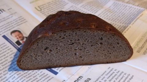 Brot auf Vorrat kaufen und einfrieren - immer schnell etwas Brot für Aufschnitt bereit, wenn Freunde kommen. Ein lachsfarbener Brotlaib liegt auf einer Zeitung, der Schnitt zeigt die dunkle Krume und die krosse Kruste.