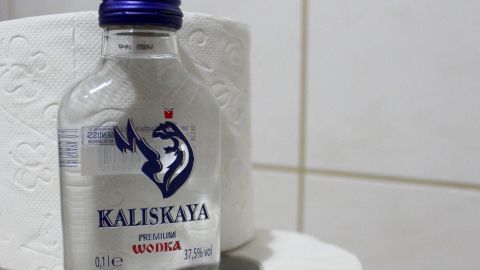 Natürlich nur dann sinnvoll, wenn keine weiteren Medikamente genommen wurden, sonst erwarten einen ernsthaftere Folgen. Eine Flasche Wodka steht auf einem Toilettenpapierstapel in einem Badezimmer, was auf einen möglichen Durchfall hinweist.