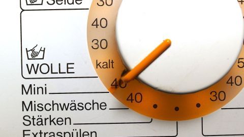 Zum Schmunzeln: Essen in Kochbeuteltüten energiesparend in der Waschmaschine garen. Ein Waschmaschinenregler zeigt Einstellungen für Wolle und Mischwäsche, um energiesparend zu kochen.
