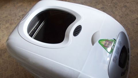 Ein Brotbackautomat steht auf einem Tisch und zeigt eine Öffnung oben, bereit zum Backen von Brot.