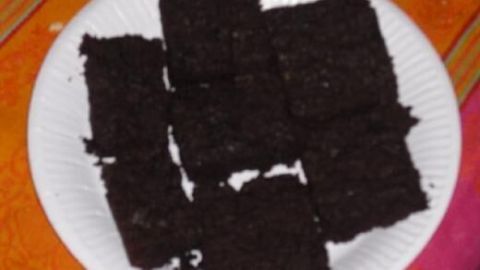 Brownies liegen auf einem weißen Teller, arrangiert auf einem orangen Tischtuch.