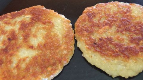 Man braucht für ein paar Rösti nicht den Backofen anzuschalten. Es ist viel einfacher, sie kurz in der Mikrowelle anzutauen und in den Toaster zu schieben! Zwei goldbraune Rösti aus dem Toaster liegen nebeneinander in einer Pfanne und warten darauf, serviert zu werden.