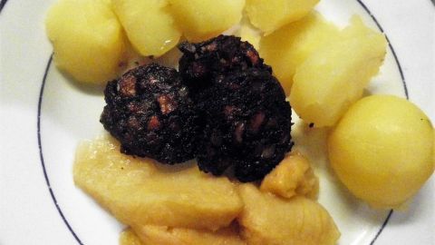 Kartoffeln und Blutwurst auf Teller, kombiniert mit Apfelmus. Traditionelles deutsches Gericht, serviert als „Himmel und Erde“.