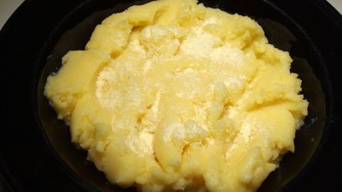 Eine große Portion Kartoffelbreipulver liegt in einer schwarzen Schale, sie zeigt eine cremige, weiche Konsistenz.