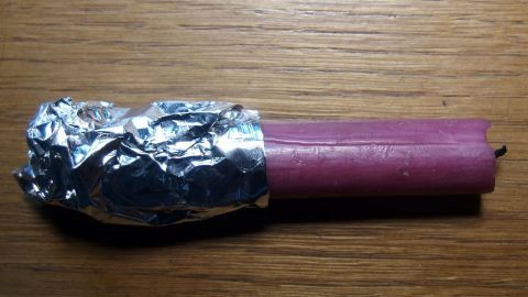 Stabilisiere deine Kerzen im Halter ganz einfach mit Alufolie: Die umwickelte Basis sorgt für sicheren Halt. So bleibt deine Deko intakt, ohne zu wackeln. Ein schneller, effektiver Trick für Zuhause! Eine Kerze ist mit Alufolie umwickelt, um sie zu stabilisieren. Sie liegt auf einer Holzoberfläche, bereit zum Einsatz.
