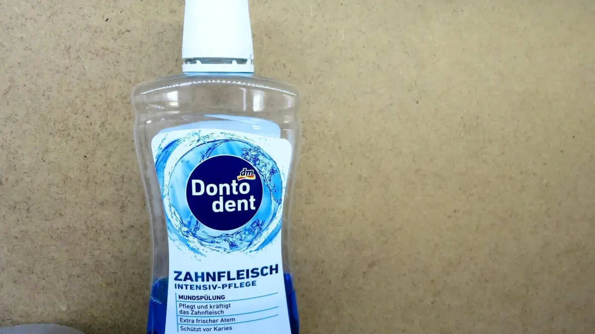 Flasche Donodent Zahnfleisch Intensiv-Pflege Mundsp&uuml;lung steht auf Holzregal. Text: Ohne Alkohol, sch&uuml;tzt vor Karies.