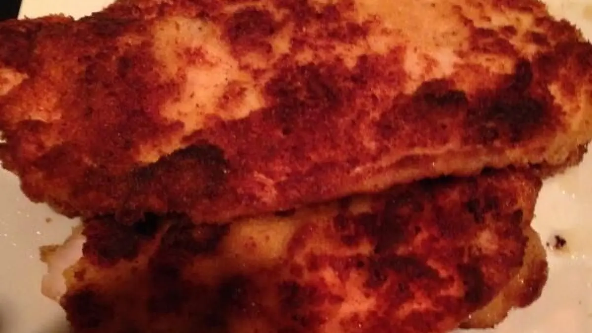 Zwei perfekt gebratene Schnitzel liegen auf einem wei&szlig;en Teller, knusprig und goldbraun, bereit zum Servieren.