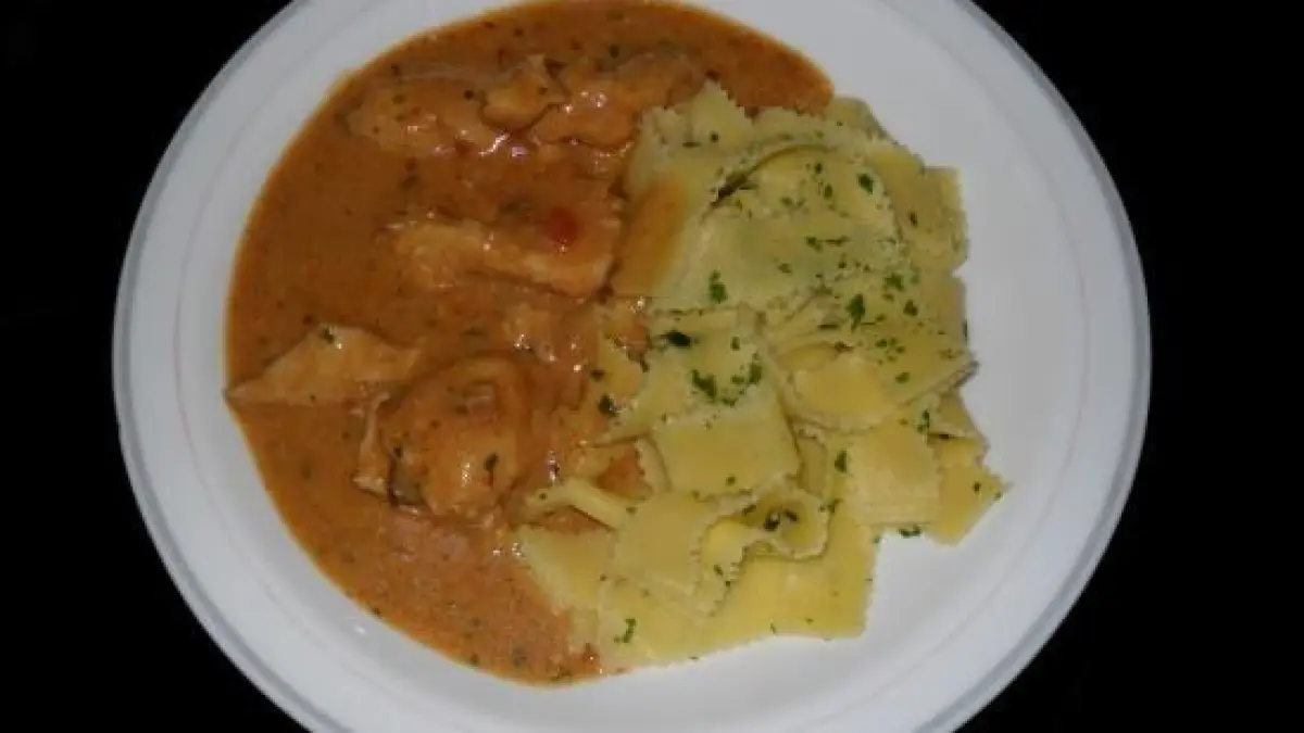 Auf einem wei&szlig;en Teller liegt H&auml;hnchengeschnetzeltes in einer w&uuml;rzigen Sauce, begleitet von Kartoffeln und Kr&auml;utern.
