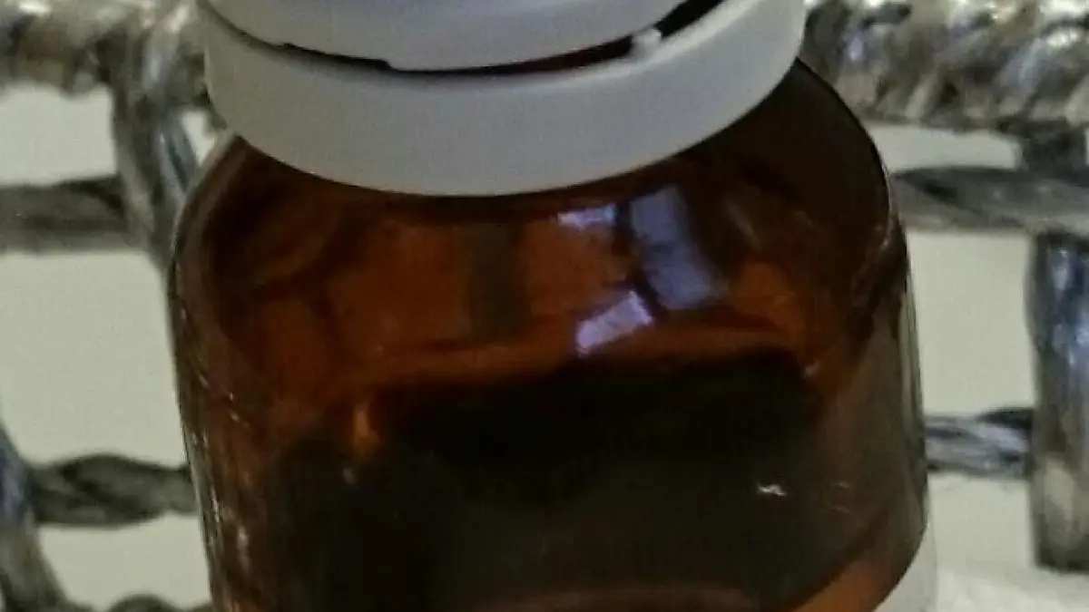 Ein braunes Fl&auml;schchen mit einer wei&szlig;en Kappe steht auf einem Tisch, beschriftet mit "Mandel&ouml;l". Es ist Teil der Umgebung f&uuml;r alternative Pflegeprodukte.
