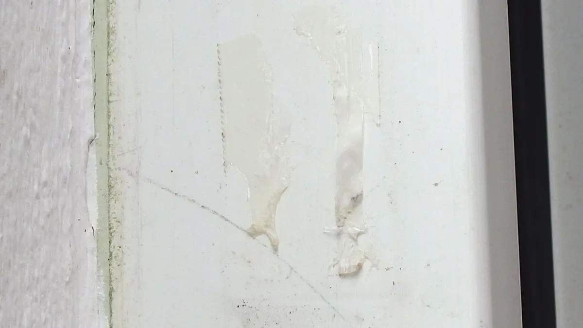 Eine Wand mit Kunststoffen zeigt Kleberreste, w&auml;hrend der Bereich um die Stelle sauber und unbesch&auml;digt wirkt.