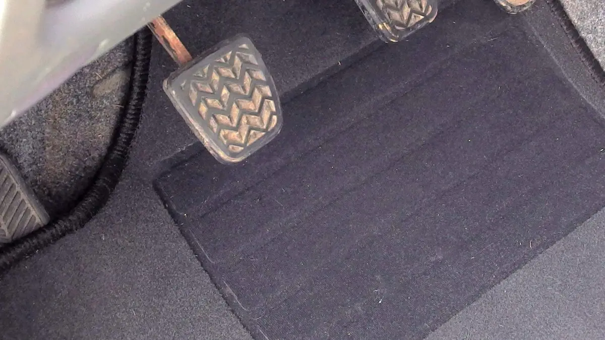 Eine Fu&szlig;matte liegt vor einem Fahrpedal im Auto, wobei sie stabilisiert werden sollte, um Rutschen zu verhindern.