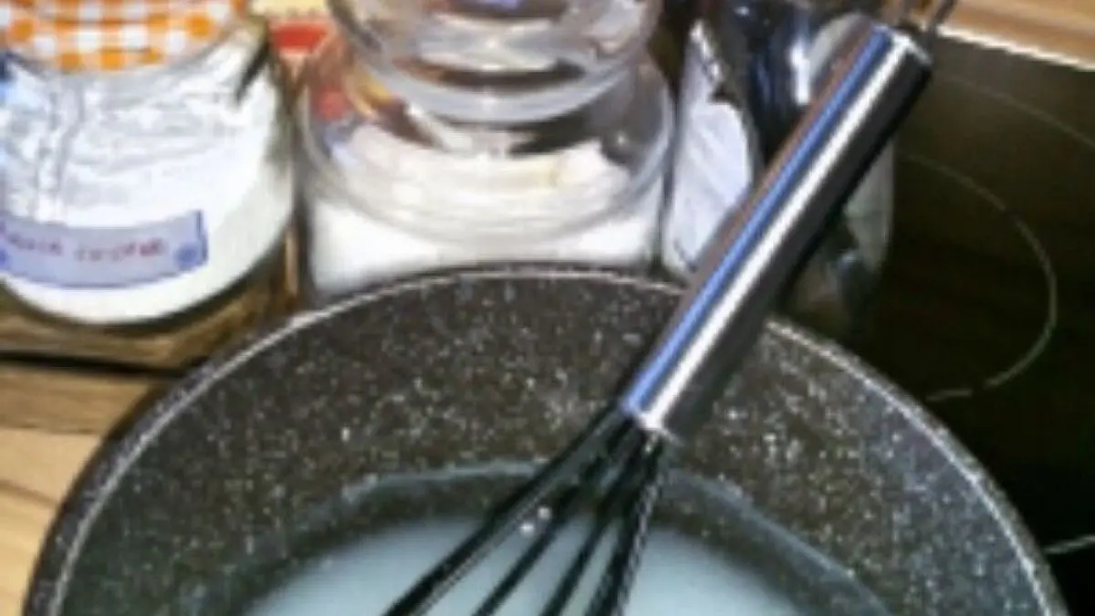 Ein Kochtopf mit einer cremigen Mischung, w&auml;hrend Zutaten f&uuml;r ein WC-Gel wie Mondamin und &auml;therische &Ouml;le vorbereitet werden.