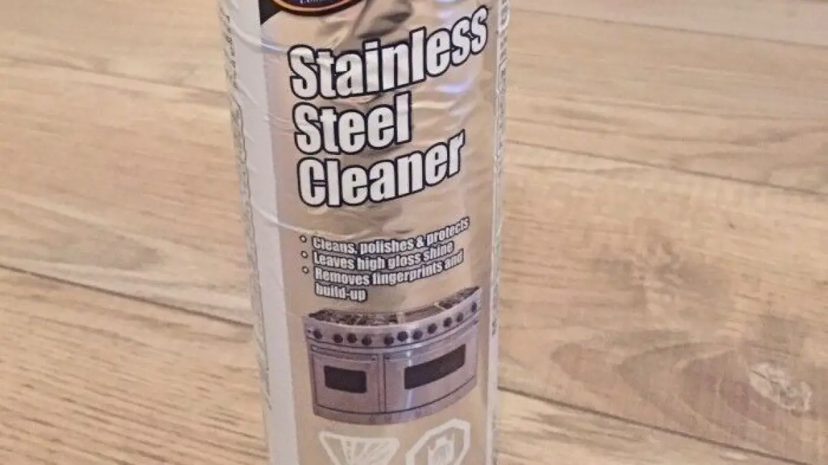 Ein Spray f&uuml;r die Reinigung von Edelstahl steht auf einem klaren, holz&auml;hnlichen Fu&szlig;boden. Es zielt darauf ab, Klebereste zu entfernen.