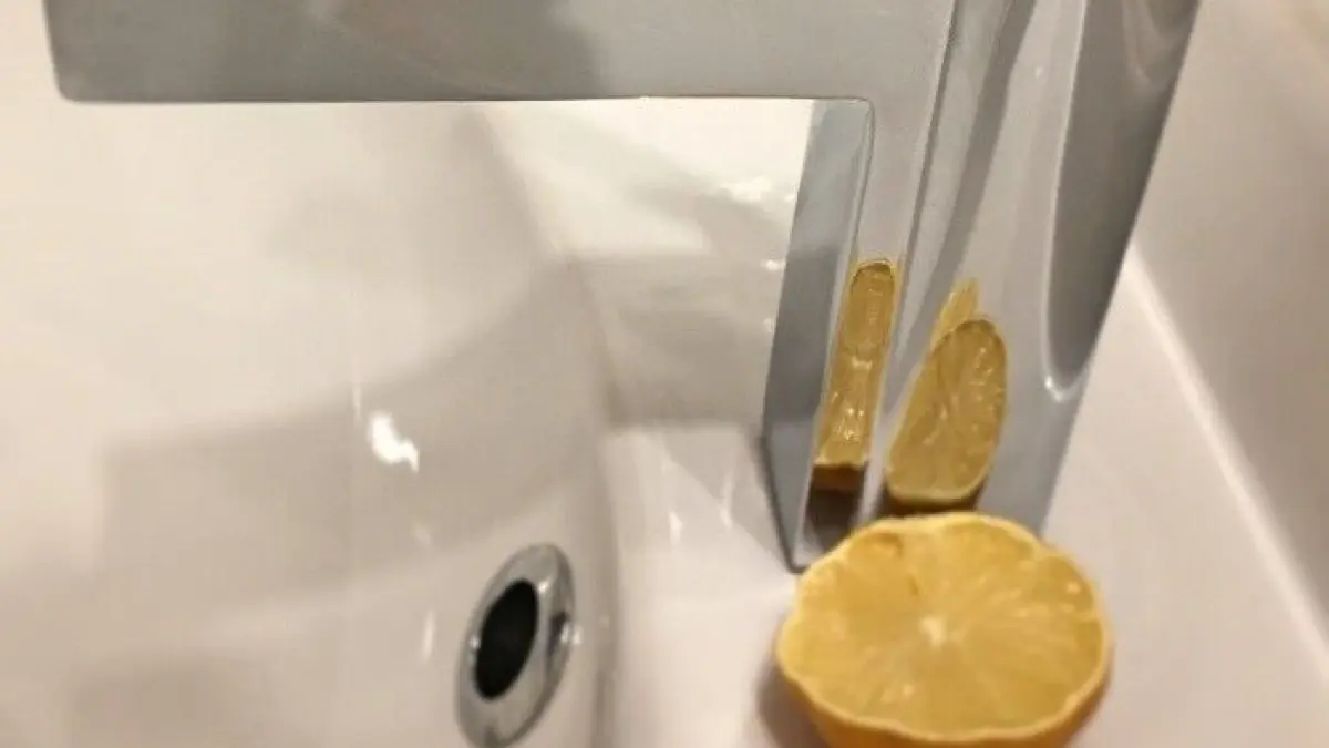 Eine moderne Wasserarmatur steht neben ausgepressten Zitronen in einem Waschbecken, in einem Badezimmer-Szenario.