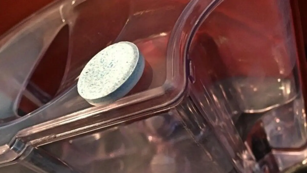 Eine Kaffeemaschine mit einem Reinigungstablette in einem Wassertank, bereit f&uuml;r die Reinigung.