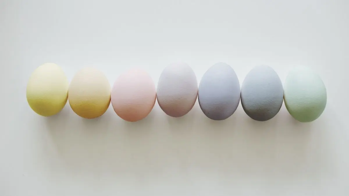 Bunte, nat&uuml;rlich gef&auml;rbte Ostereier liegen in einer Reihe auf einem hellen Hintergrund und zeigen sanfte Pastellfarben.