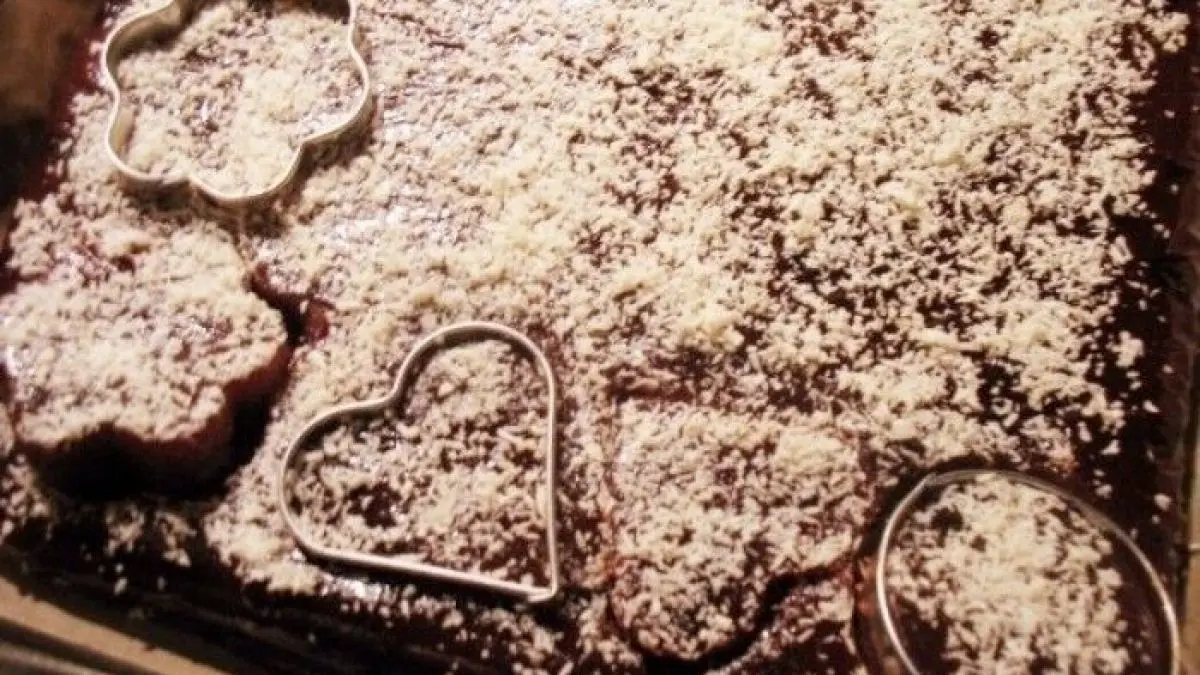 Quittenbrot mit Cranberries und Barberries liegt auf einem Blech, dekoriert mit Puderzucker und ausgestochenen Formen.