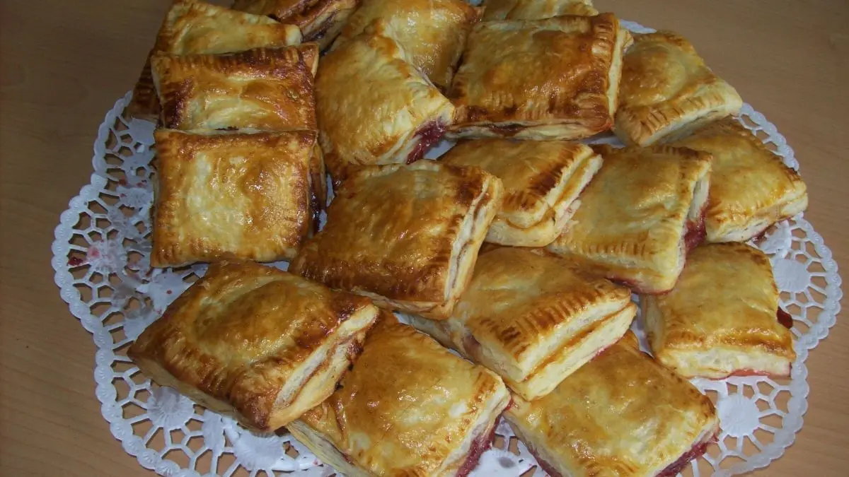 S&uuml;&szlig;e Bl&auml;tterteig-Kissen liegen auf einer Unterlage, gl&auml;nzend gebacken und verstr&ouml;men einen k&ouml;stlichen Duft in einem hellen Raum.