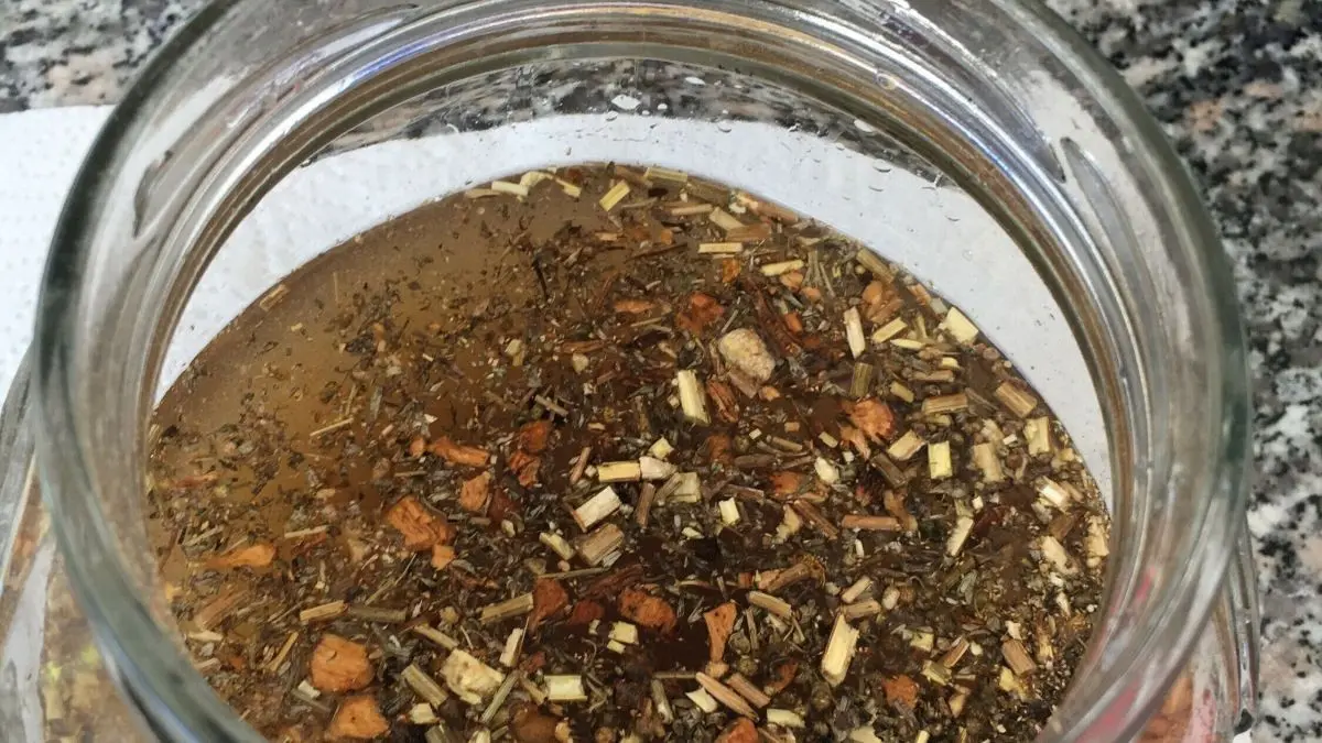 Ein Glas mit Schwedenkr&auml;utern ist gef&uuml;llt mit Fl&uuml;ssigkeit und Kr&auml;utermischung zum Ansetzen von Schwedenbitter.