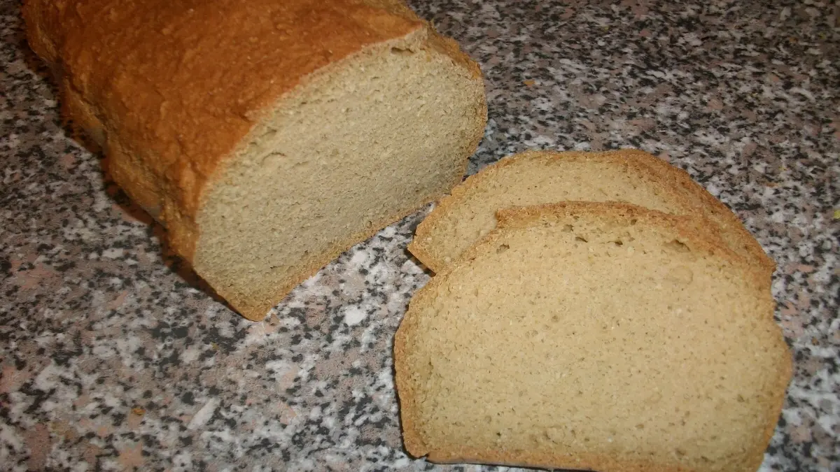 Eiwei&szlig;brot liegt auf einer Arbeitsfl&auml;che, zwei Scheiben sind abgeschnitten, bereit zum Genie&szlig;en oder Servieren.