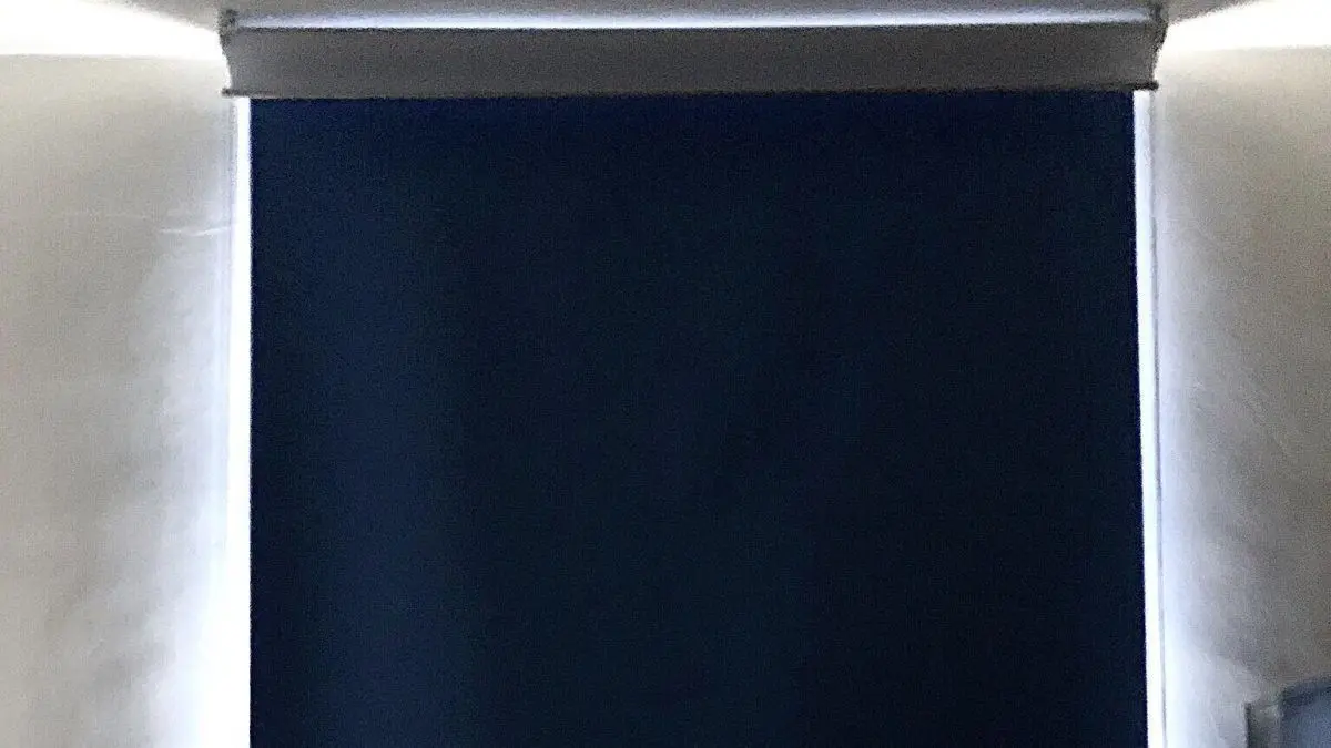 Das Verdunkelungsrollo ist vollst&auml;ndig heruntergelassen und blockiert das Licht in einem Raum mit hellen W&auml;nden.
