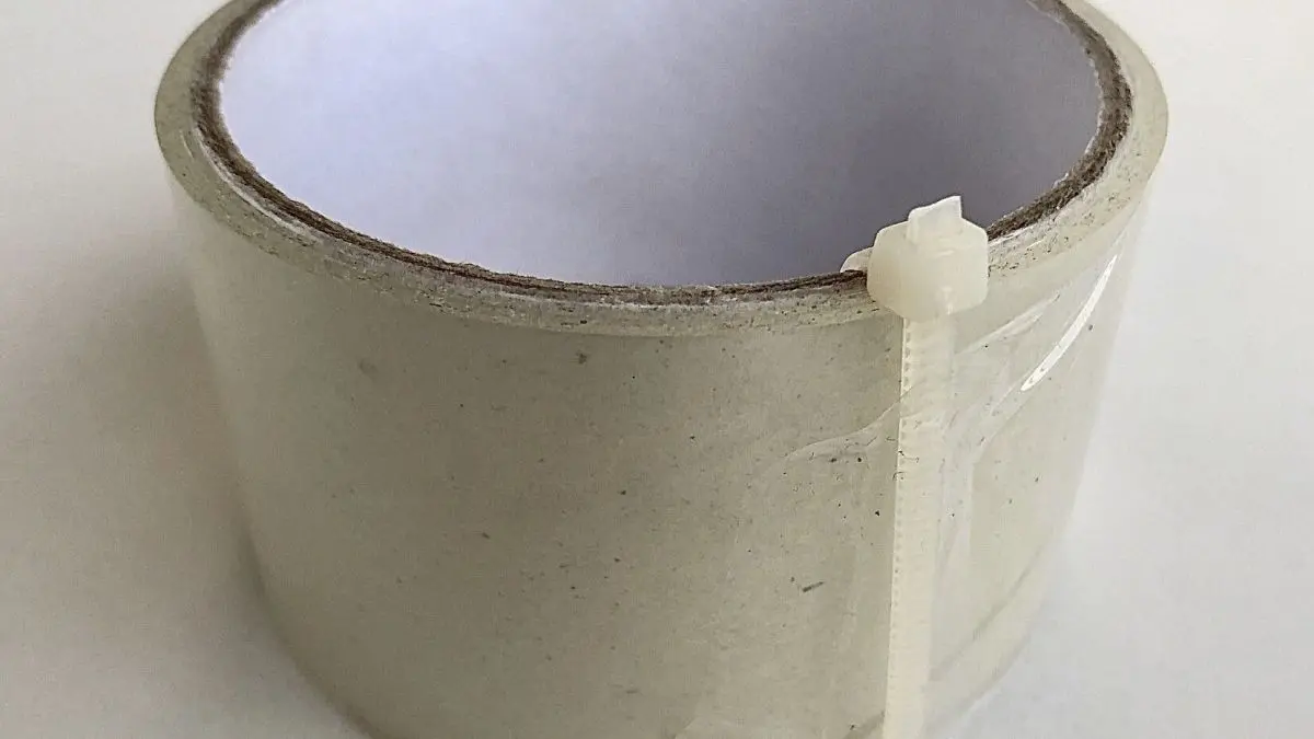 Ein Klebeband-Rolle ist mit einem Kabelbinder gesichert, steht auf einem hellen Untergrund und zeigt eine praktische L&ouml;sung.
