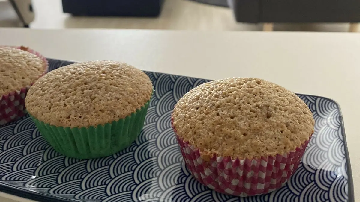 Saftige Nussmuffins liegen auf einem dekorativen Teller, w&auml;hrend ein modernes Wohnzimmer im Hintergrund sichtbar ist.