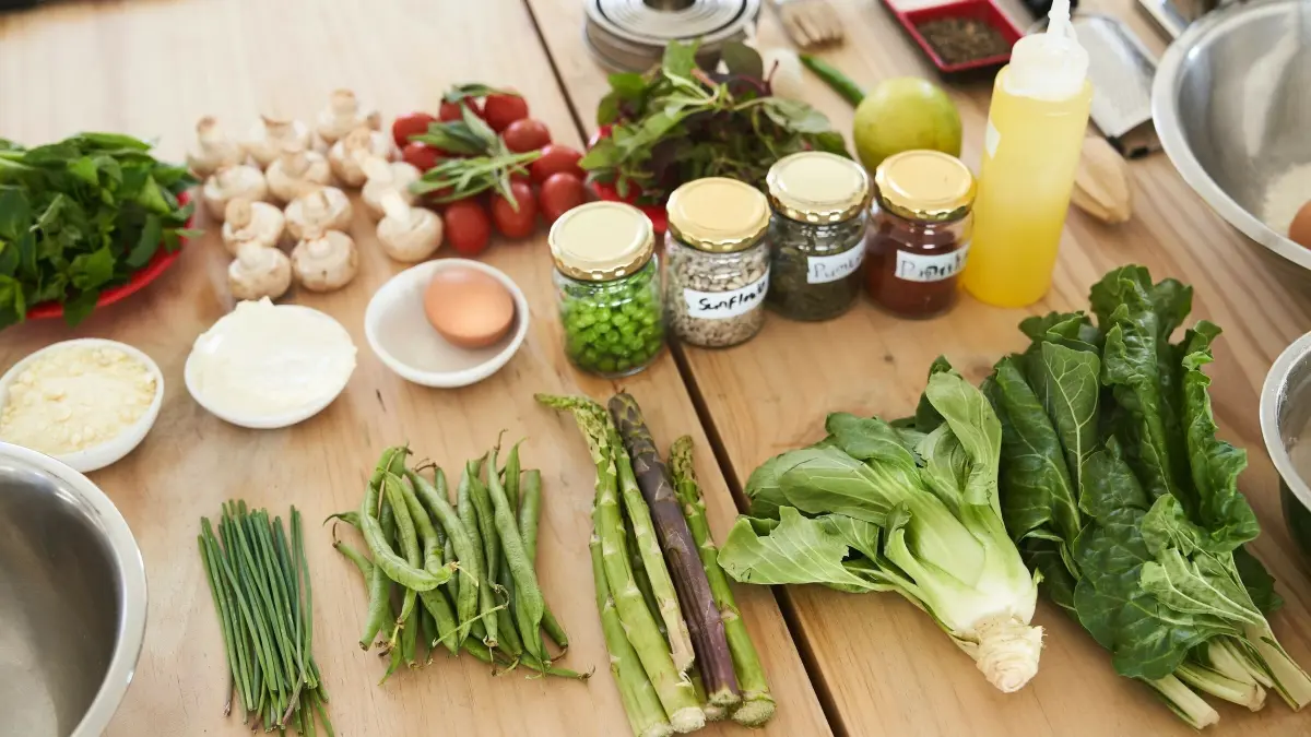 Frische Gem&uuml;se und Zutaten liegen auf dem Tisch, bereit f&uuml;r die Zubereitung einer vegetarischen Mahlzeit in einer K&uuml;che.