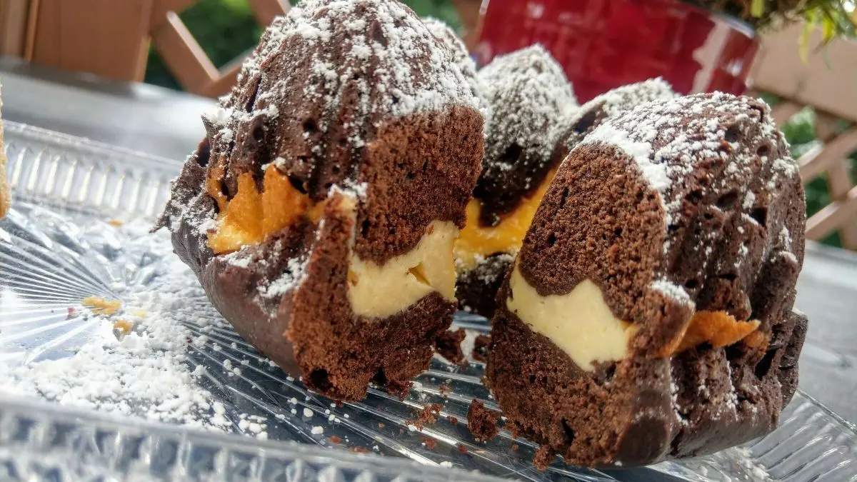 Der gefrorene Schoko-Gugelhupf mit K&auml;sekuchenf&uuml;llung zeigt sich appetitlich auf einem Teller, umgeben von frischem Ambiente.