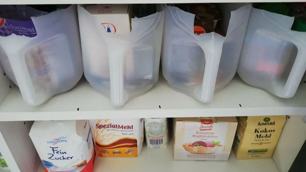 Vorratsbeh&auml;lter aus Kanistern stehen ordentlich in einem Regal und enthalten verschiedene Lebensmittel in durchsichtigen Beh&auml;ltern.