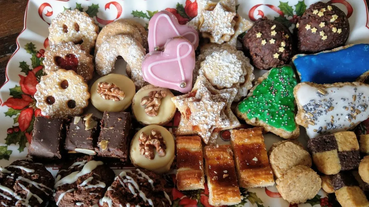 Auf einer dekorativen Platte liegen verschiedene Weihnachtskekse, die bunt verziert sind, gefragt f&uuml;r stressfreie Weihnachtsb&auml;ckerei.