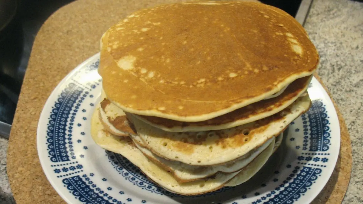 Auf einem blauen Teller liegen mehrere goldbraune Dinkel-Eierkuchen &uuml;bereinander, bereit zum Servieren.
