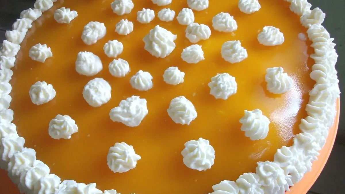 Eine k&ouml;stliche Mandarinensahne mit einer leuchtend orangefarbenen Oberfl&auml;che, dekoriert mit Sahneh&auml;ufchen.