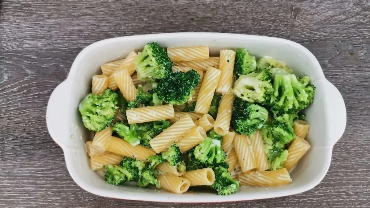 Tortiglioni und Brokkoli sind in einer wei&szlig;en Sch&uuml;ssel angerichtet, umgeben von einem holz&auml;hnlichen Tisch.