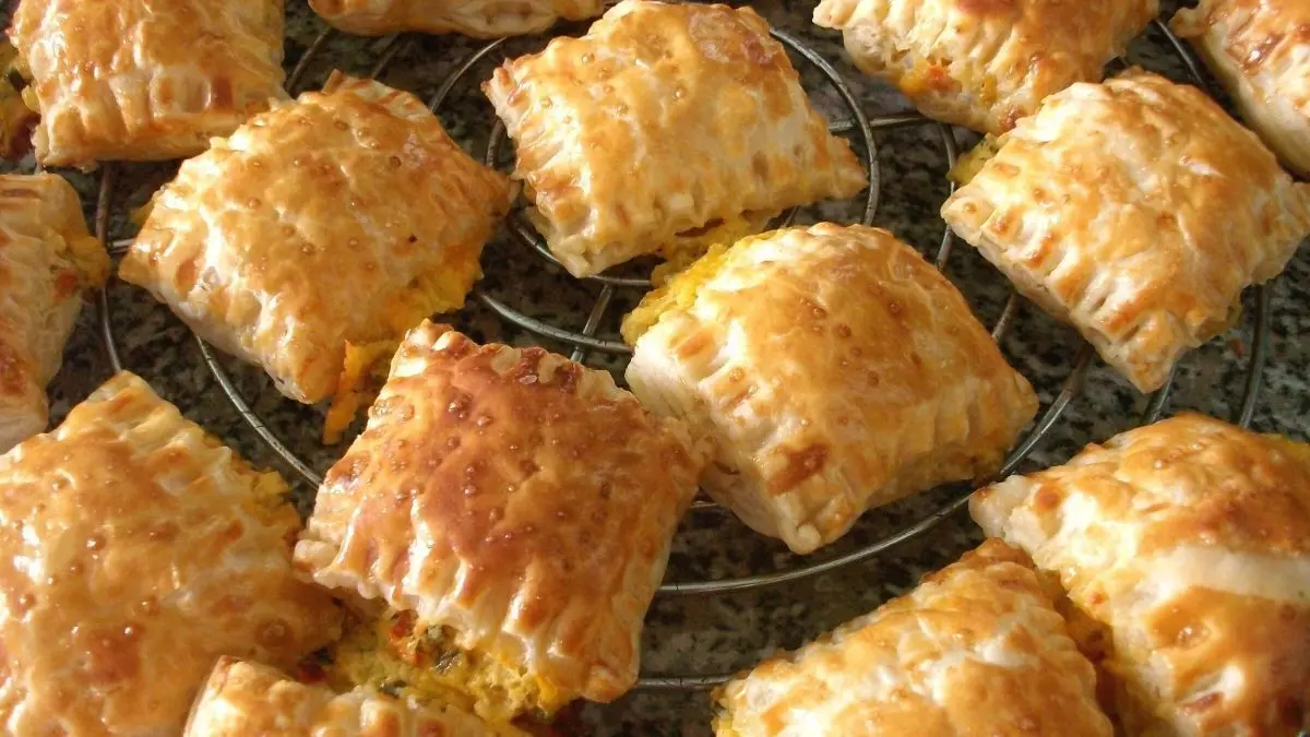 Goldene Bl&auml;tterteigtaschen liegen auf einem Gitter, dampfend und lecker gef&uuml;llt, bereit zum Servieren.