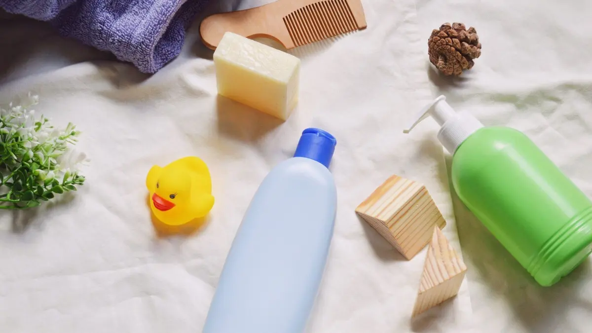 Eine blaue Flasche Duschgel und eine gr&uuml;ne Flasche Shampoo liegen auf einem wei&szlig;en Tuch, umgeben von Accessoires.