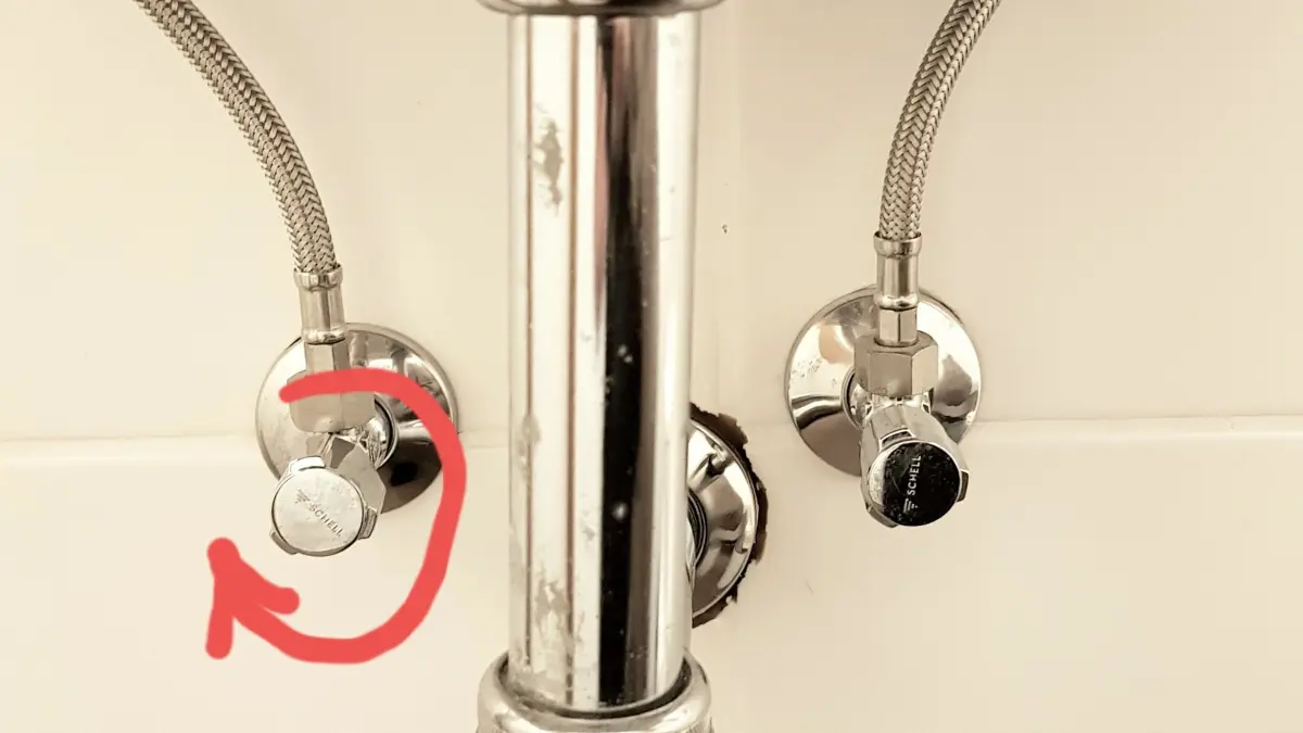 Ein Wasserhahn mit verchromtem Rohr wird abgedreht, um Warmwasser im Sommer zu sparen, in einem Badezimmer.